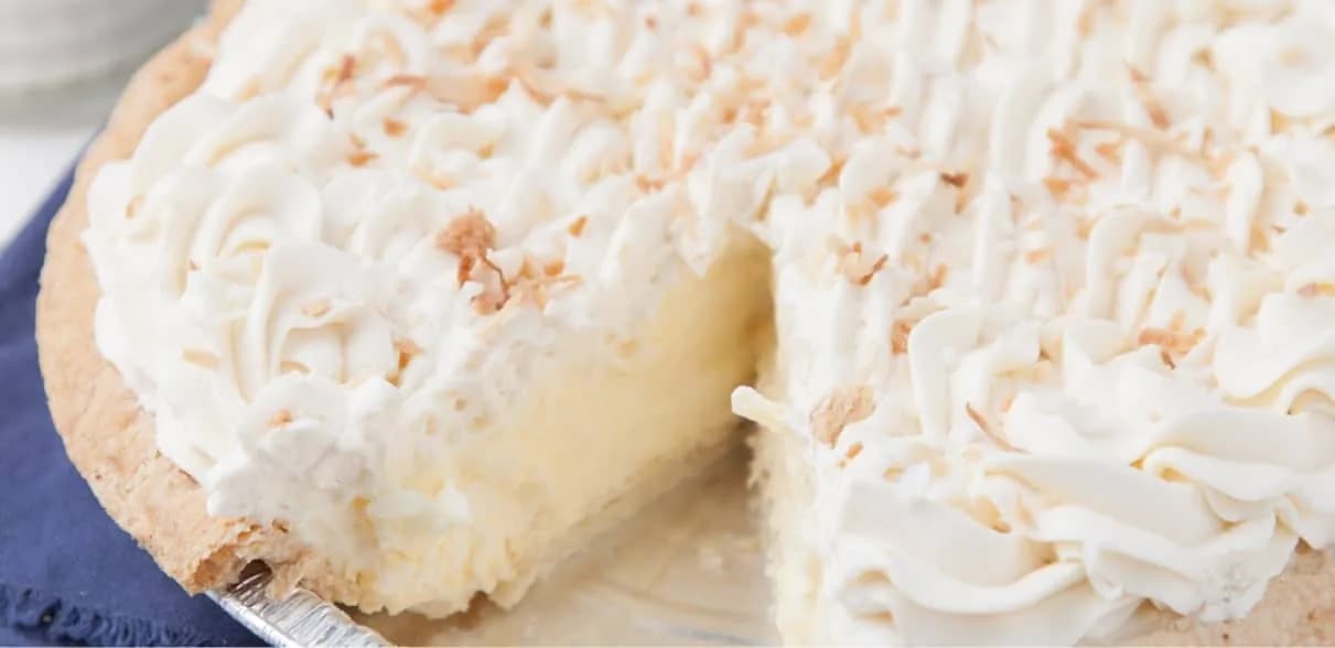 Slice cut from a coconut cream pie topped with toasted meringue