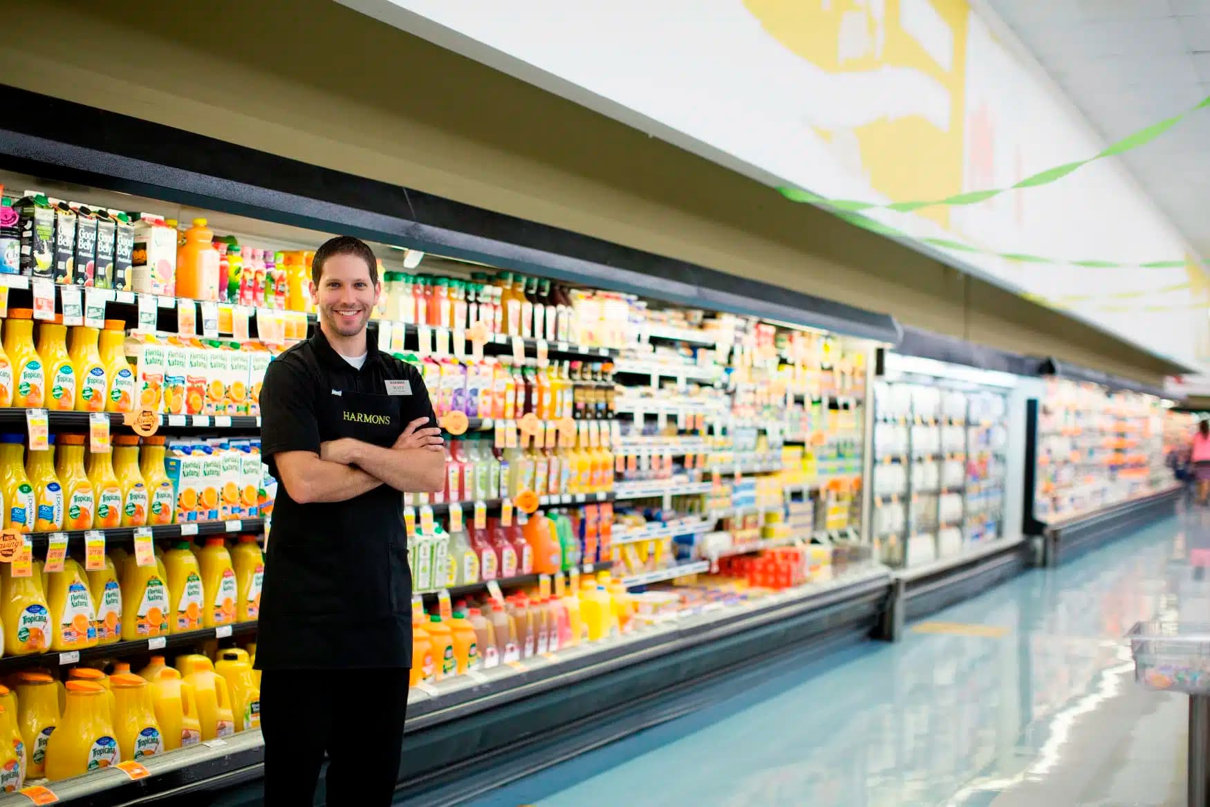 Harmons dairy associate standing in front of the refrigerated dairy case