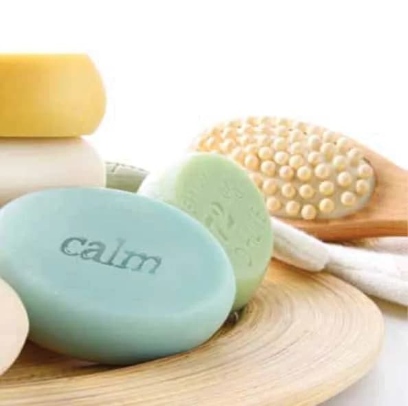 Assortment of soaps and a body brush on a wooden tray