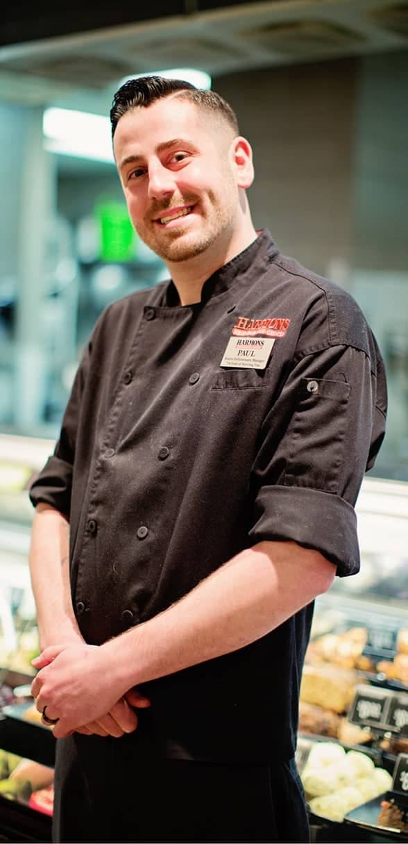 Harmons kitchen chef smiling beside the hot food counter