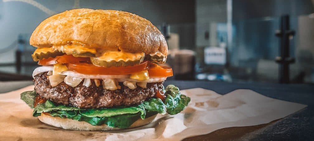 Beef burger with chipotle aioli, tomato and pickles on a ciabatta bun